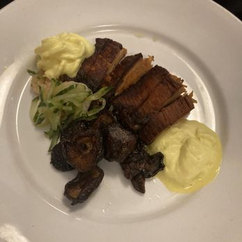 Dante's Fire - Miso-Glazed Pork Belly - A white plate holds slices of grilled pork belly with a crispy exterior, accompanied by mashed potatoes and a side of sautéed green vegetables. The presentation is simple, with the food arranged neatly on the plate, suitable for a meal at a restaurant or gastropub. - Cocktail Bars Near Me - Tucson, Arizona