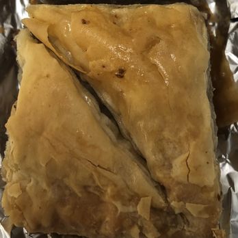 Athens Bakery - Baklava - A piece of baklava with a golden, flaky top layer rests on aluminum foil, showing its layered pastry exterior. - Bakeries Near Me - Teaneck, New Jersey