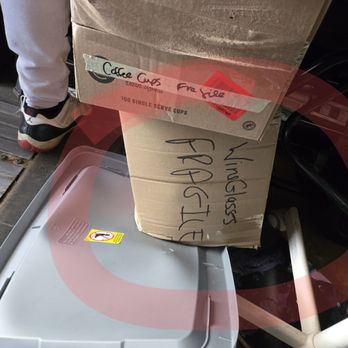Ox Movers - A cardboard box marked "Living Room Fragile" is positioned on a plastic tray, with handwritten labels and a note indicating "Coffee Cups" and "Free Side." The scene appears to be part of a moving or storage setup. - Furniture Assembly Near Me