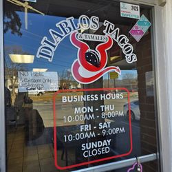 Diablos Tacos & Tamales - The Business Hours painted on the front door of the restaurant.
