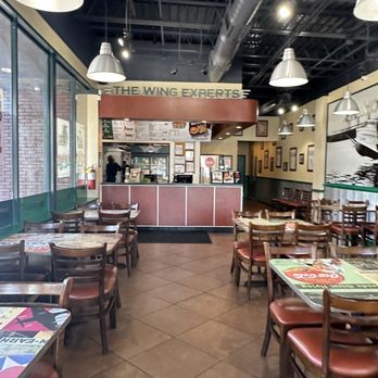 Wingstop - the inside of a restaurant with tables and chairs - Chicken Wings Near Me - Norcross, Georgia