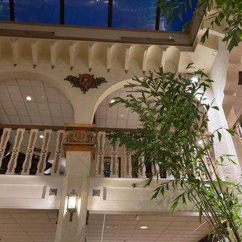 The Columbia - The ambiance is superb! - The image shows an indoor space with a balcony, decorative arches, and a large green plant in the foreground, with ceiling lights and architectural details. - Spanish Near Me - St Augustine, Florida