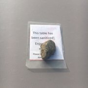 Photo of Tioga Gas Mart & Whoa Nellie Deli - Lee Vining, CA, United States. Rock and sign signifying the tables that were sanitized.