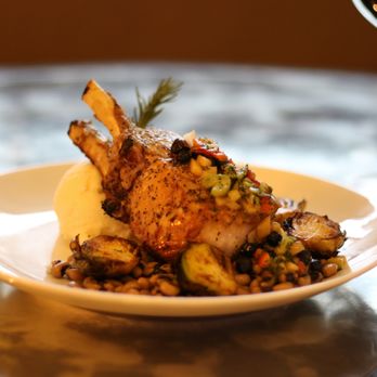 The Dispatch | Magnolia Houston - Pan Seared Pork Chop bed of herb and cheddar grits, topped with a brandy apple demi sauce, served with roasted brussels sprouts and black ey - Bars Near Me - Houston, Texas The Dispatch | Magnolia Houston - Pan Seared Pork Chop bed of herb and cheddar grits, topped with a brandy apple demi sauce, served with roasted brussels sprouts and black ey - Bars Near Me - Houston, Texas