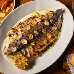 Bazaar Mar by José Andrés - Perfectly charred whole fish that has been grilled over a live fire, topped with crispy garlic chips.