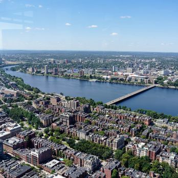 View Boston - A high-angle photograph of Boston showing the Charles River, bridges, and city buildings under a blue sky. - Observatories Near Me - Boston, Massachusetts