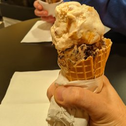 a person holding a cone of ice cream a person holding a cone of ice cream