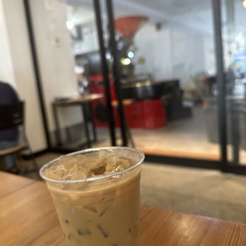 Plowshares Coffee Roasters - Iced vanilla latte in foreground. In-house roasting in the background. - Coffee Roasteries Near Me - New York, New York Plowshares Coffee Roasters - Iced vanilla latte in foreground. In-house roasting in the background. - Coffee Roasteries Near Me - New York, New York