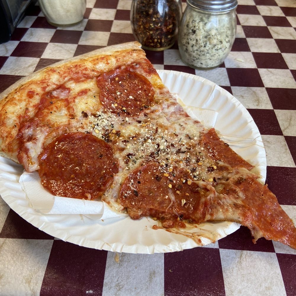 Cibelli's - XL Pepperoni pizza slice with seasoned Parmesan cheese and crushed red pepper - Pizza Near Me - Sisters, Oregon Cibelli's - XL Pepperoni pizza slice with seasoned Parmesan cheese and crushed red pepper - Pizza Near Me - Sisters, Oregon