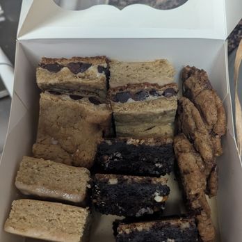 Perfect Bites Catering - Desserts - A white box contains various dessert bars and cookies, including chocolate chip, Oreo, and oatmeal cookies, from Perfect Bites Catering. - Caterers Near Me