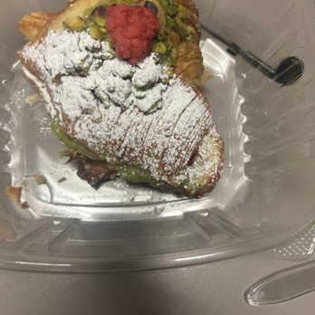 Creampuff - Raspberry Pistachio croissant - A pastry with powdered sugar, chopped pistachios, and a raspberry on top, placed in a clear plastic container. - Donuts Near Me - Phoenix, Arizona