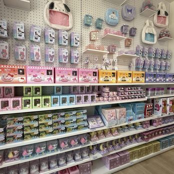 Miniso - Merch - A retail display at Miniso in Riverside, CA, features plush toys, stationery, and accessories organized on white shelves. Items include plush animal heads, small storage boxes, and various character-themed products in pastel colors like pink, purple, blue, and green. The display is set against a pegboard wall, with products neatly arranged in rows and sections, showcasing a variety of cute and decorative items. - Accessories Near Me - Riverside, California