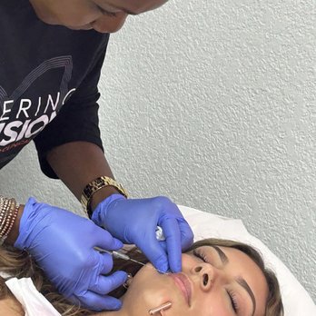 Aesthetic Lab - A woman with closed eyes undergoes a cosmetic procedure involving injections, performed by a practitioner wearing blue gloves in a clinical setting. - Medical Spas Near Me - Modesto, California