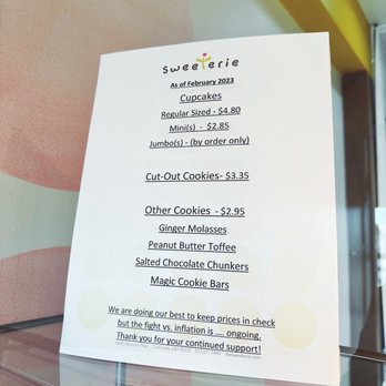 Sweeterie - A printed menu from Sweeterie bakery displays cupcake and cookie options, including prices and special notes, with a reflection on a glass surface. - Desserts Near Me - Cincinnati, Ohio