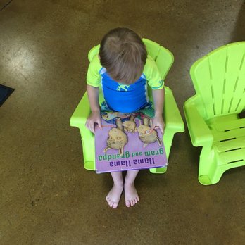 Goldfish Swim School - Carmel - Our little fish reading in the book corner before his lesson starts - Swimming Lessons/Schools Near Me - Carmel, Indiana
