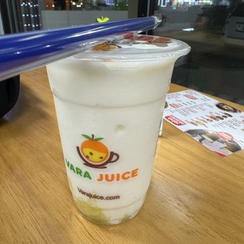 Vara juice - a plastic cup of yogurt - A fruit smoothie in a clear cup with the Vara Juice logo, placed on a wooden table near a window at night. - Juice Bars & Smoothies Near Me - Bridgeview, Illinois
