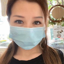 Classic Set 80pcs - A woman with brown hair and gray eyes wears a light blue face mask indoors, with a window showing trees and cars outside.