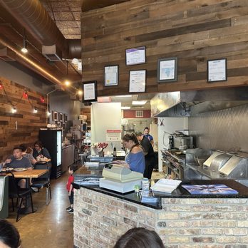 Chicago Breakfast Restaurant - A casual restaurant interior featuring a brick counter, wooden wall panels, and a visible kitchen area with staff preparing food. - Breakfast & Brunch Near Me - Chicago, Illinois