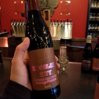 Contrary Brewing Co - a person holding a bottle of beer - Breweries Near Me - Muscatine, Iowa