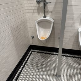 Very clean bath room that's a screen in urinal.