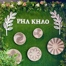Interior - A decorative wall features the name 'Pha Khao' on a green grass backdrop, with floral borders and woven baskets arranged below.