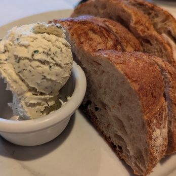 Don's Lighthouse - Complimentary bread and butter - Three slices of toasted bread with a golden-brown crust are presented on a white plate, accompanied by a scoop of butter or spread in a small dish. - Seafood Near Me - Cleveland, Ohio