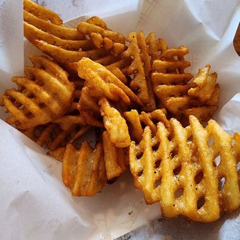 Chicken Licks - Waffle fries - A serving of waffle fries with a golden-brown, crispy texture, placed on white paper in a basket, typical of casual dining or bar settings. - Chicken Wings Near Me - Sun Prairie, Wisconsin