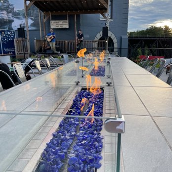 The District - View of long fire table with stage in back. - American Near Me - Wisconsin Dells, Wisconsin The District - View of long fire table with stage in back. - American Near Me - Wisconsin Dells, Wisconsin