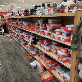 Target - A retail store aisle features a wooden shelf filled with numerous shoe boxes, with shoes displayed on top and some boxes on the floor. - Department Stores Near Me - Bowie, Maryland