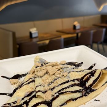 Griddled Crepes & Paninis - Campfire Crepe, a crepe filled with melted chocolate and marshmallows, drizzled with chocolate, topped with crushed graham crackers - Coffee & Tea Near Me - Castle Rock, Colorado Griddled Crepes & Paninis - Campfire Crepe, a crepe filled with melted chocolate and marshmallows, drizzled with chocolate, topped with crushed graham crackers - Coffee & Tea Near Me - Castle Rock, Colorado