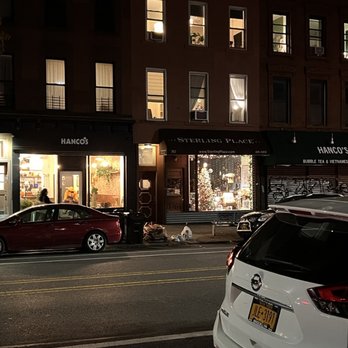 Hanco’s - Exterior shot from across the street - Nighttime street scene showing storefronts, parked cars, and lit interior windows of businesses in Brooklyn, NY. - Vietnamese Near Me - Brooklyn, New York