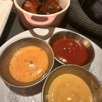 Tonic - Tater Tots. Sauce - A bowl of meatballs with sauce is placed on a plate with three small cups of different dipping sauces, likely at a restaurant. - New American Near Me - Washington, DC, District of Columbia