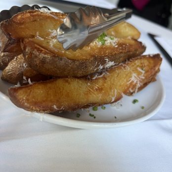 Forest - Home Fries - A dish of crispy potato wedges topped with grated cheese and chopped herbs, served on a white plate with tongs. - New American Near Me - Birmingham, Michigan