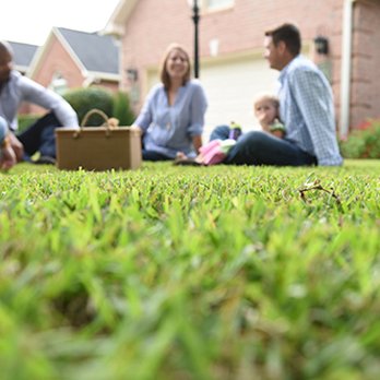 Weed Man - a family sitting on the grass in front of a house - Pest Control Near Me - Whitehouse, Texas Weed Man - a family sitting on the grass in front of a house - Pest Control Near Me - Whitehouse, Texas