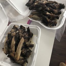 Baby Back Ribs - Two white foam containers hold cooked beef ribs, with one container stacked on top of the other, on a white table.