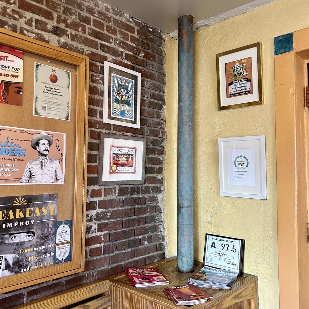 Laughing Seed Cafe - a brick wall with posters on it - Vegetarian Near Me - Asheville, North Carolina