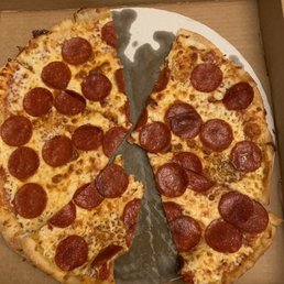Pepperoni pizza - A pepperoni pizza with melted cheese and evenly distributed pepperoni slices is shown in a cardboard pizza box. Two slices have been removed, revealing the crust and toppings. The pizza appears freshly baked with a golden-brown crust.