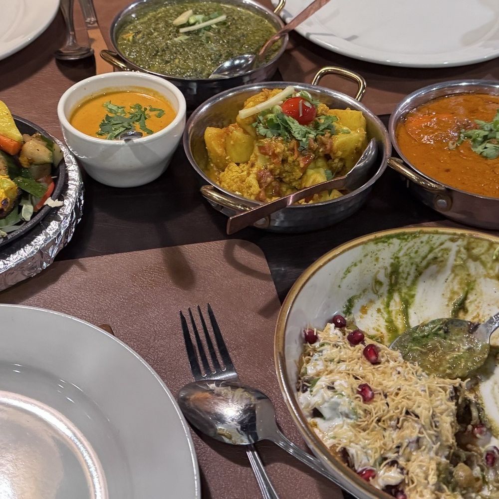 Shrimp tandoor on sizzling skillet, paneer, aloo gabi, chicken tikka masala and 3/4 eaten samosa chat Shrimp tandoor on sizzling skillet, paneer, aloo gabi, chicken tikka masala and 3/4 eaten samosa chat