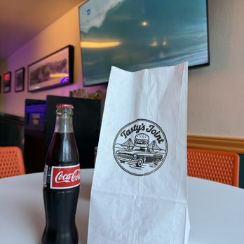 Tasty's Joint - Bottle of Coca-Cola and bag of food - Burgers Near Me - Sausalito, California Tasty's Joint - Bottle of Coca-Cola and bag of food - Burgers Near Me - Sausalito, California