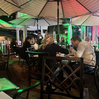 Olive Branch - a group of people sitting at a table under an umbrella - Bars Near Me - Mount Dora, Florida