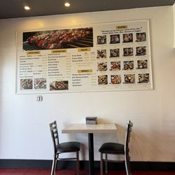 Some of the menu on the wall and a table for dine in.