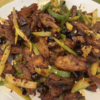 Fat Dragon - Spicy Sautéed Pork Intestines / 干煸肥肠 - $16 - Delicious but not to eat as a whole meal. Great to share with 3-4 others. - A dish featuring sautéed pork intestines with green onions, chili peppers, and black beans, served on a white plate. - Asian Fusion Near Me - Austin, Texas