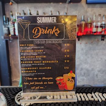 Checkers Old Munchen - Summer drink menu - A drink menu sign featuring summer cocktails like cucumber cosmo, lychee martini, and strawberry jalapeño margarita, priced at $12. - American Near Me - Pompano Beach, Florida
