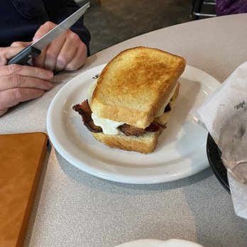 CJ's Bar & Grill - Chicken bacon Parmesan - A toasted sandwich with bacon, egg, and possibly cheese is served on a white plate at a restaurant table. - Bars Near Me - Fall River, Wisconsin