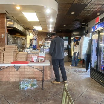 Rosa's Pizza - a man standing in front of a vending machine - Pizza Near Me - Middle Village, New York