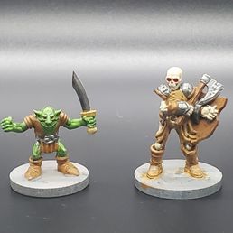 two figurines of a man with a sword and a skull two figurines of a man with a sword and a skull