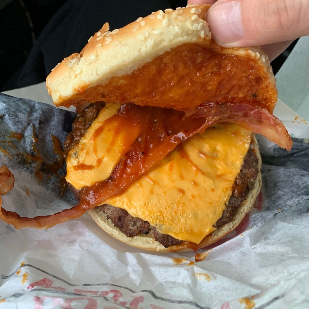 a hand holding a cheeseburger