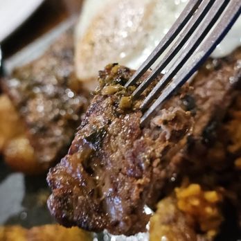 Aji Fusion - A fork holds a piece of the steak from The Bisteck a lo Pobre main course. - Latin American Near Me - Roanoke, Virginia