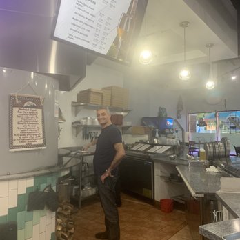 Custom Pie and Bar - One of the owners monitoring the wood fire pizza oven. - Pizza Near Me - Moorpark, California Custom Pie and Bar - One of the owners monitoring the wood fire pizza oven. - Pizza Near Me - Moorpark, California