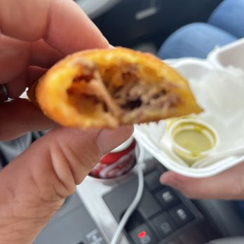 Sabor Colombia - a hand holding a half eaten food item - Empanadas Near Me Sabor Colombia - a hand holding a half eaten food item - Empanadas Near Me